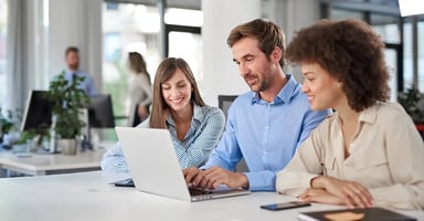 Business professionals collaborating in an office around a laptop