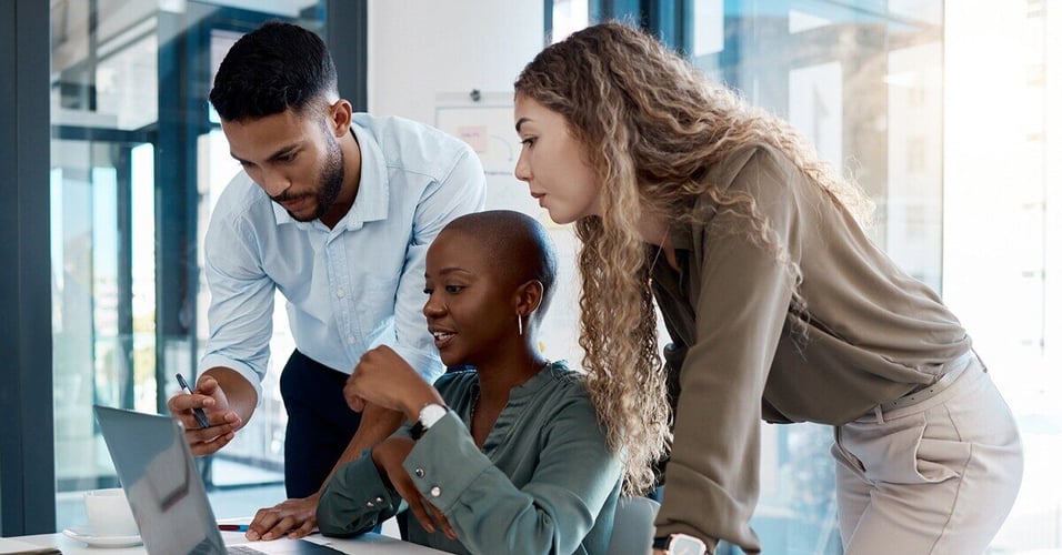 Colleagues collaborating around a laptop