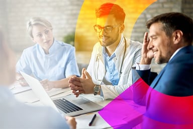 Group of health care professionals working at a table around a laptop computer.