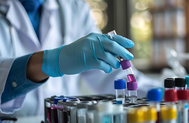 Gloved hand working with test tubes and vials in a lab