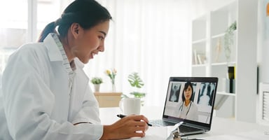Medical Professional interacting with another person virtually on a laptop