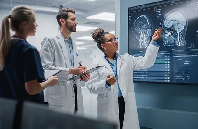 Health care professionals reviewing x-ray scans on large television