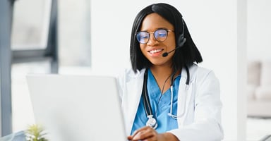 Health care worker wearing headset working on laptop