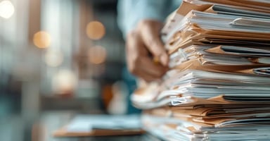 Large pile of documents and files on an office desk