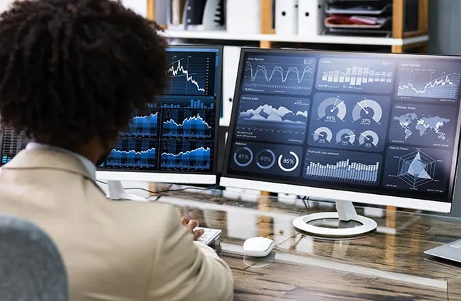 Person looking at data on multiple computer monitors and laptop