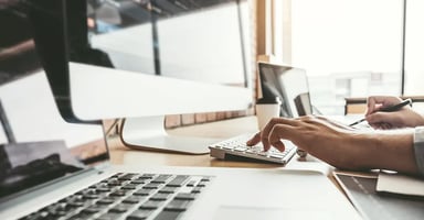 Person working on laptop and desktop devices
