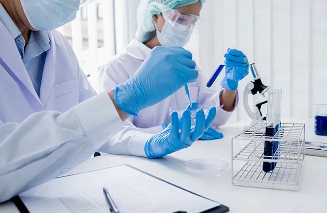 Two lab techs working with petri dishes test tubs in clean room