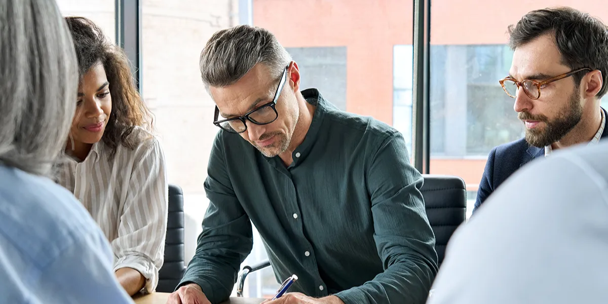 professional-business-people-collaborating-at-a-conference-table-ss-2021639240-1200x627