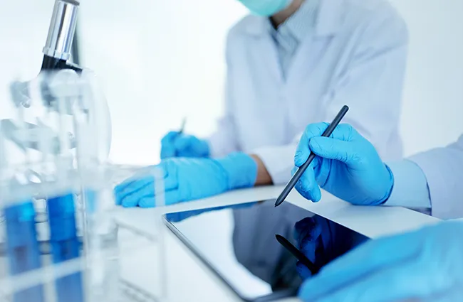 Lab techs working at a desk with tablet devices